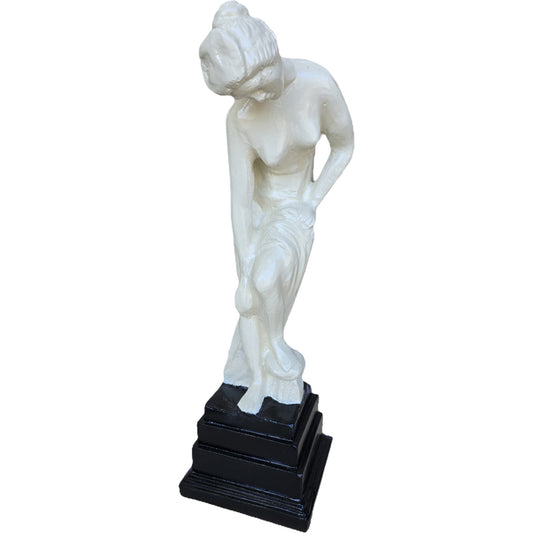 White cast aluminum statue of a woman bending, on black pedestal, for garden or home decor