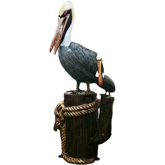 Cast aluminum pelican statue perched on wooden post with rope, outdoor yard decor