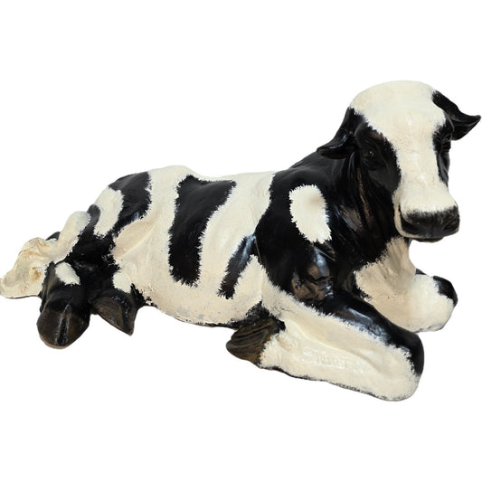 Black and white cast aluminum cow statue for yard or home decor, lying down with realistic spots.