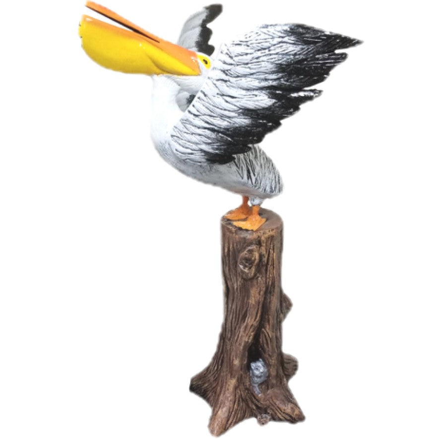 Cast aluminum pelican statue perched on tree stump, backyard decor with spread wings