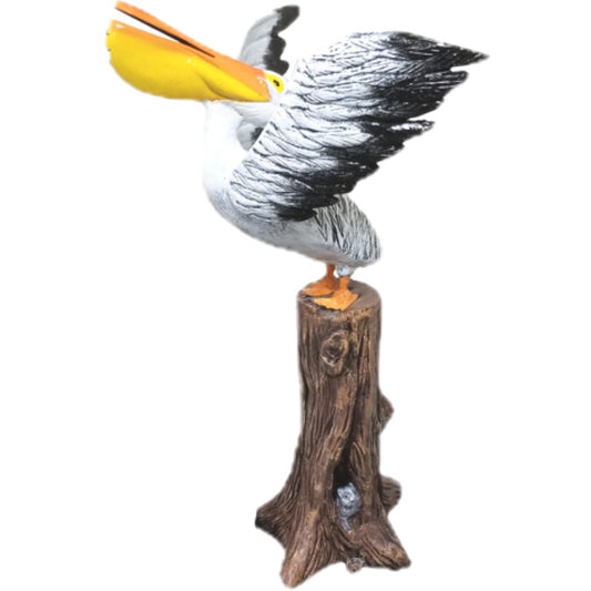 Cast aluminum pelican statue perched on tree stump, backyard decor with spread wings